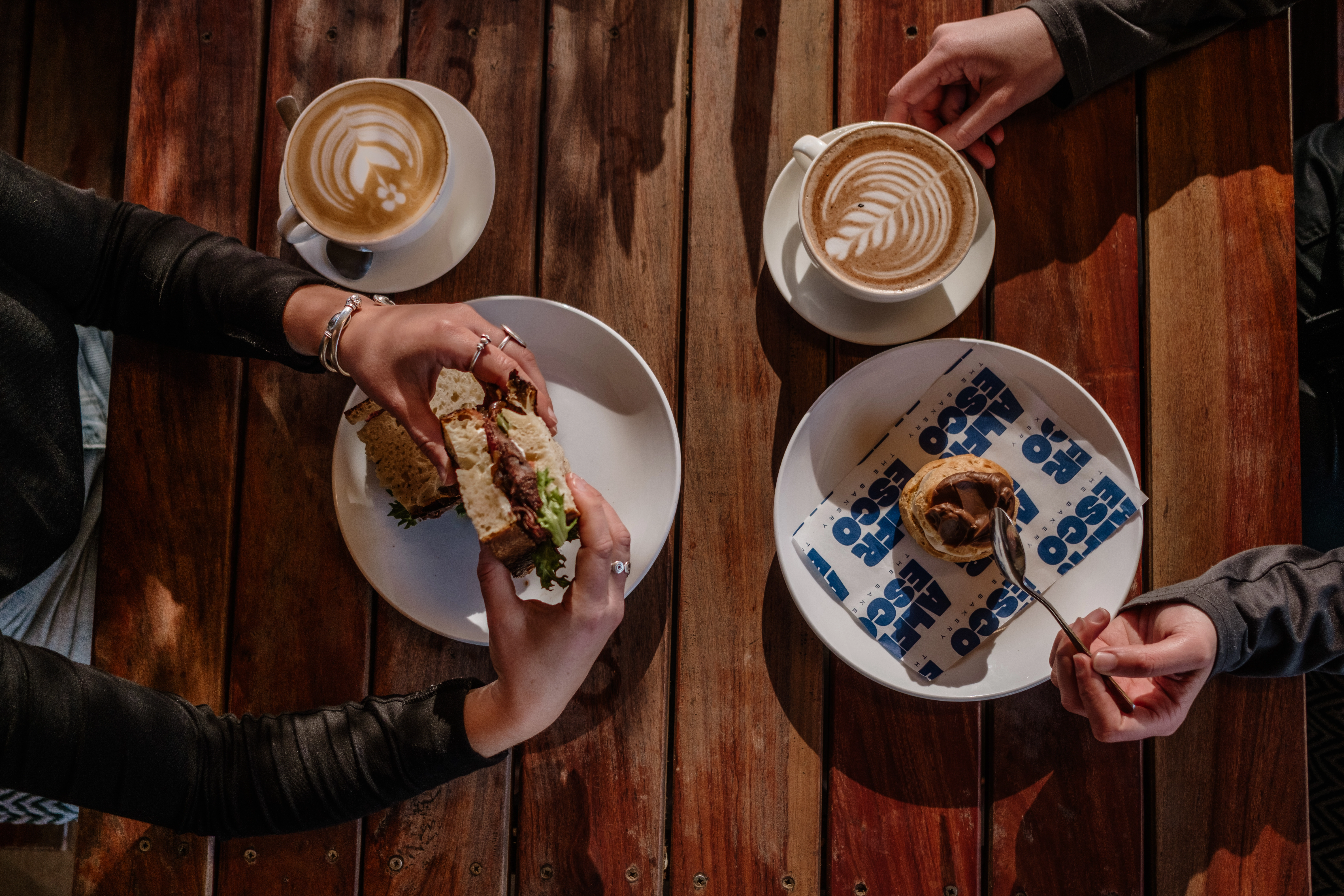 Aesthetic table setting with two people's hands, plates and coffee cups with milk styling