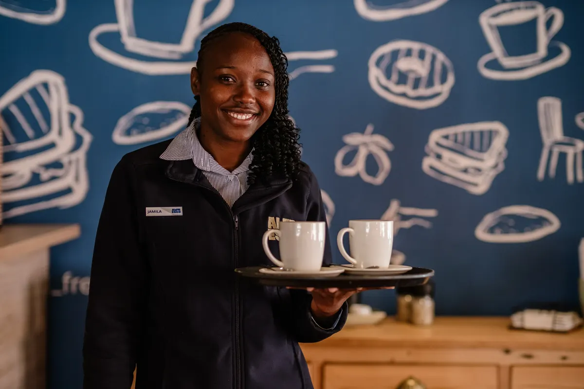 Alfresco team member carrying a tray with two mugs