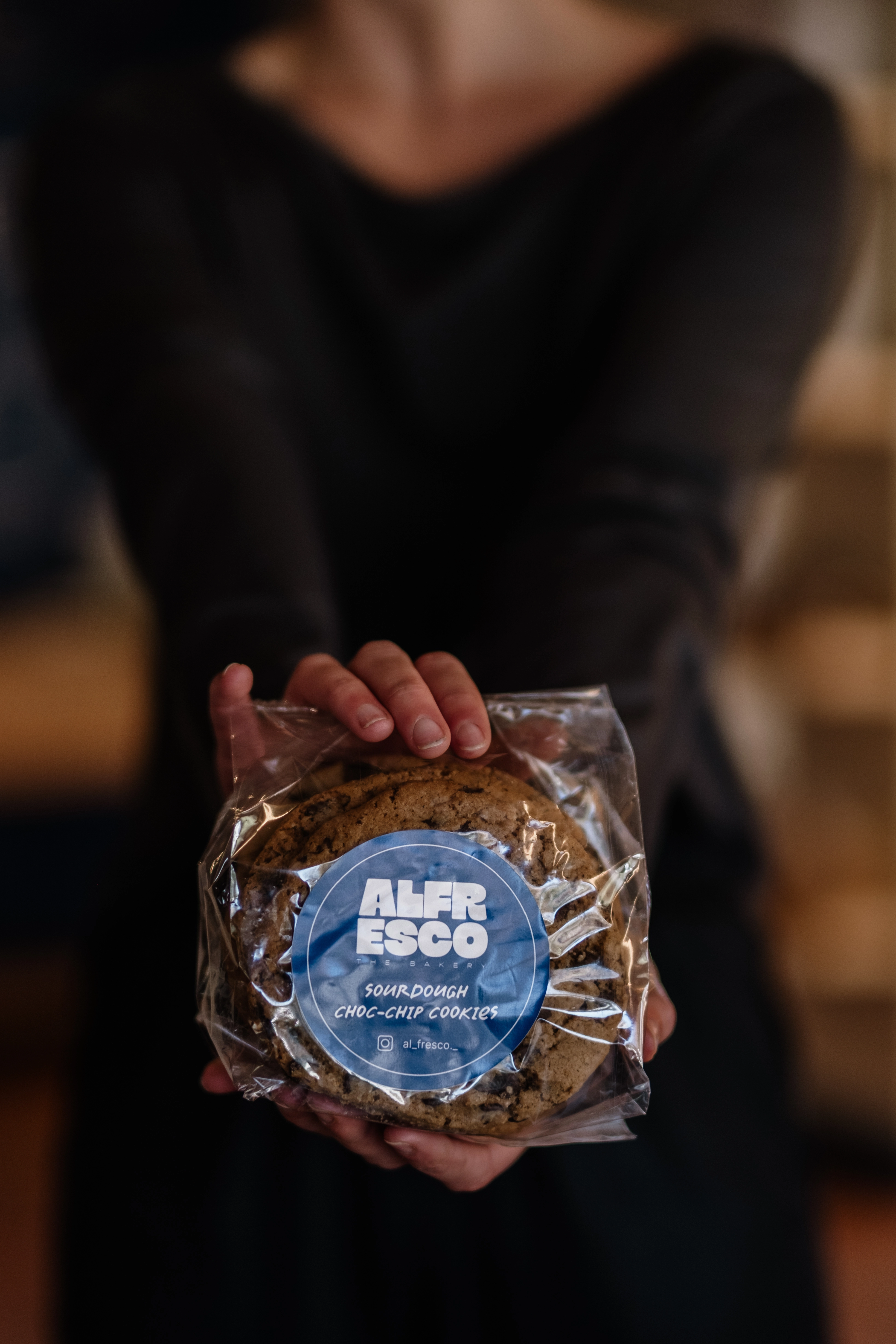 Hand holding packet of sourdough cookies facing the lens